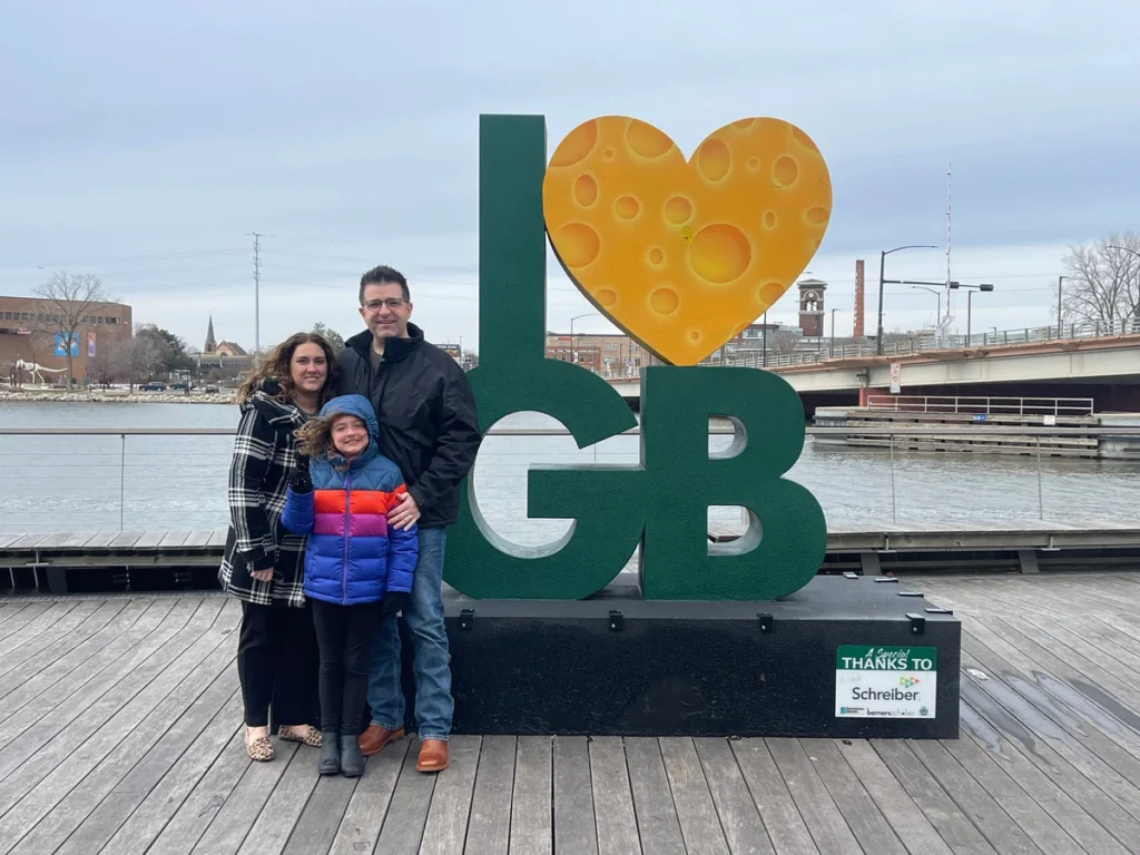 Family of 3 posing beside I love GB