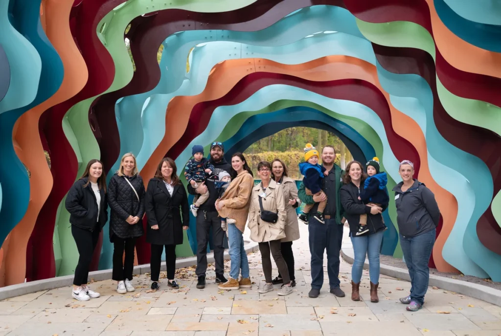 Group of visitors posing in front of a sculpture